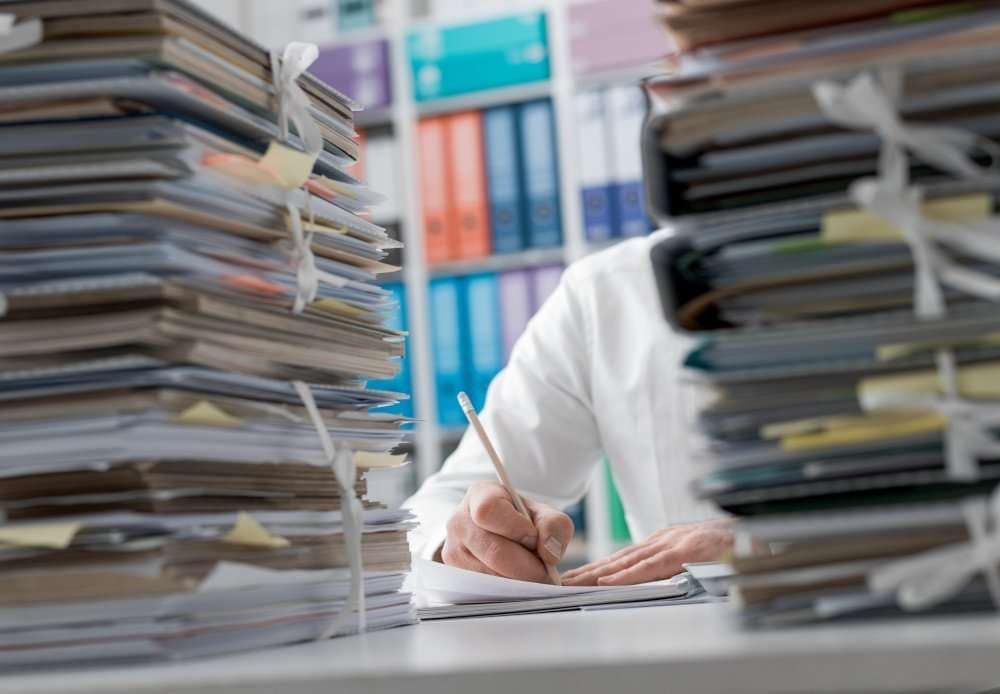 Photograph of documents on a desk behind which someone can be seen writing and being a better lawyer