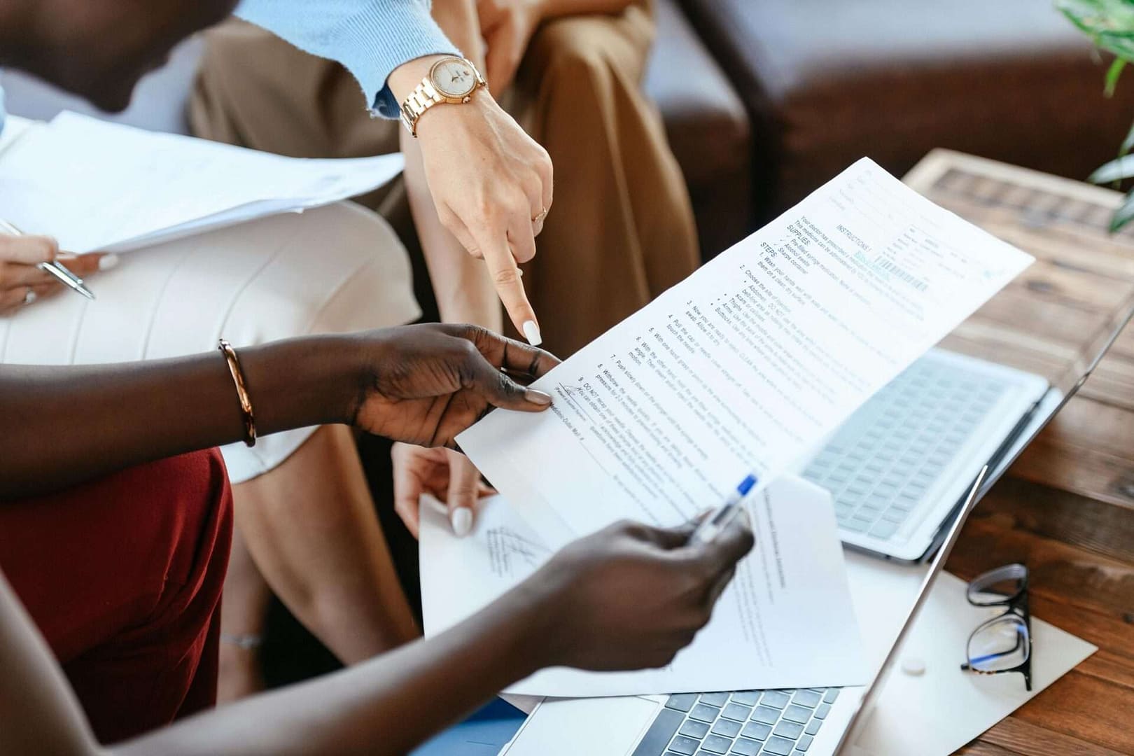Photograph of two pairs of hands handling documents and pointing to them.